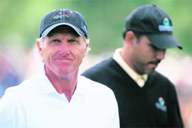 Greg Norman smiles while walking with Jeev Milkha Singh during a practice round