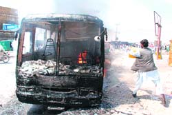 A man throws water on a burning bus during riots in Quetta on Thursday. Riots erupted in southwest Pakistan that left one policeman dead as public anger boiled over following the murder of three Baluch nationalist politicians, officials said. 