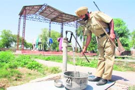 A cop, who has been housed along with 14 other cops at the private cremation ground of Chief Minister Parkash Singh Badals families at Badal village in Muktsar district, busy fetching water for household chore on Saturday.