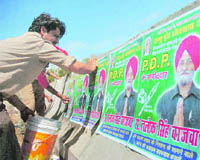  A worker of the municipal corporation removes election posters from a wall in Jammu on Saturday.