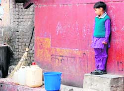 A little girl waits to fill her bucket with water in Dehradun on Sunday. 