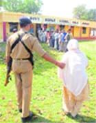 A security personnel helps an old woman reach her polling booth in Bela Jamana border village 
