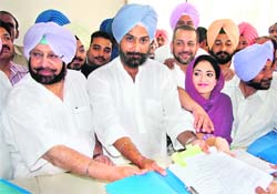 Congress candidate from Bathinda Raninder Singh files his nomination papers before the assistant returning officer in Bathinda on Friday. He is flanked by his father and former Chief Minister Amarinder Singh and wife Rishma Kaur.