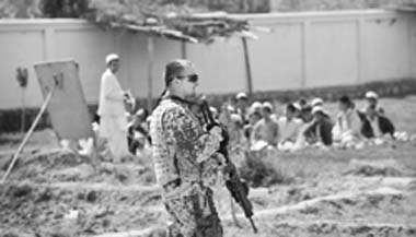 A soldier of German armed forces Bundeswehr guards a school in Emam Saheb in Kunduz province, northern Afghanistan as students study in an open air classroom 