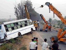 Police and administrative officials pull out a bus from the fields along the road  near Sikri village in Faridabad on Tuesday.
