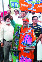 An activist wears a BJP flag and carries the election symbol of the SAD at a rally in Jalandhar on Tuesday.
