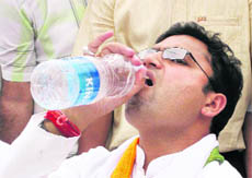Congress nominee Ashok Tanwar quenches his thirst while campaigning in a village in Sirsa on Friday.