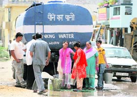 People await their turn for water in a Jammu locality