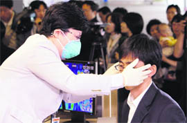 A South Korean quarantine officer checks the body temperature of a passenger arriving from China at Incheon International Airport on Tuesday