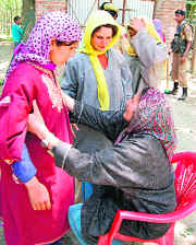 A CRPF woman jawan frisks voters outside a polling station in Pulwama district on Thursday.