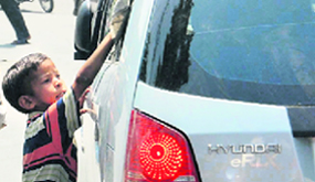 A child cleaning car windows at a traffic signal in Dehradun.