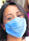 A woman wears a surgical mask with a smile drawn on it in Mexico City.  Reuters