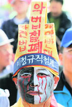 A union worker wearing mourning clothes takes part in a May Day rally denouncing Lee Myung-bak governments economic policies near the National Assembly in Seoul on Friday.