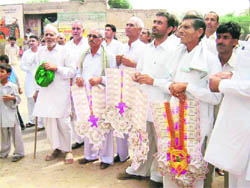 Villagers wait for the arrival of INLD supremo Om Prakash Chautala with garlands of currency notes in a village in the Sirsa LS constituency on Sunday.