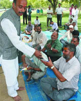 Vijay Goel distributes poll material to government employees at Boat Club in New Delhi on Monday. 