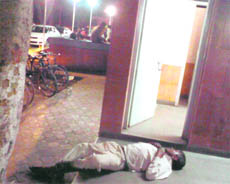 A man, in an inebriated condition, lies in front of washrooms at the night food street even as the business goes on as usual.