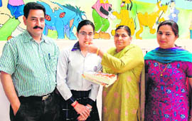 Astha Kapil, the topper in the Class X examination, being congratulated by her parents and teacher.