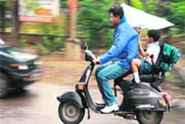 A boy tries to hold on to his umbrella on a rainy Tuesday morning in Ludhiana