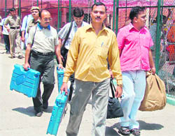 Polling staff carry electronic voting machines and other poll-related material in Karnal on Wednesday.