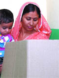 A woman with her child in arms, casts her vote in Ghaziabad on Thursday.