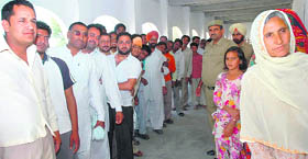 Villagers wait to cast their vote at Jallopur village in Fatehabad district on Thursday.