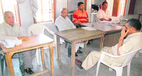 Polling officials wait for voters at Khanpur village in Kaithal district on Thursday.