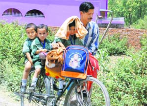A man ferries three children back from school on his bicycle at Nanurkheda village in Dehradun