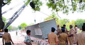 Delhi police personnel remove the container that fell over a man killing him on Mehrauli-Badarpur Road in New Delhi on Saturday.