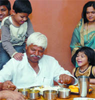 His rival Mahabal Mishra enjoys lunch with his grandchildren at his residence in New Delhi on Saturday.