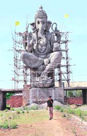 A factory worker walks in front of a 65-feet-high statue of Hindu God Ganesh situated on the New Delhi-Rohtak Highway in Bahadurgarh. The statue took more than two years to complete and cost more than Rs 1 crore. 