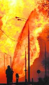 A firefighter sprays water on the wall of a building to prevent it from catching fire in Moscow on Sunday.