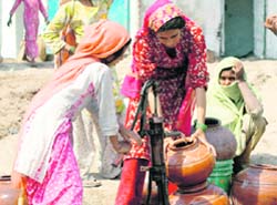 LEFT HIGH AND DRY: Village women get water from a handpump on a hot summer afternoon on the Gurgaon- Mewat road