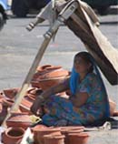 A pitcher-seller improvises a shade to escape the rays of the scorching sun.
