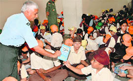 An IAF official distributes flight safety pamphlets to school students at an awareness workshop in Chandigarh on Tuesday.