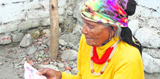An old woman in Dehradun reads an appeal by a party candidate on the eve of the last phase of the general election.