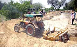Farmers busy in plugging the breach in Ramsara sub-canal near Abohar.