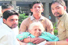 Chanan Kaur being helped out of the polling station by her family members at Dhanas village
