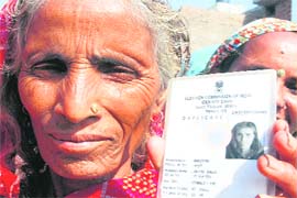 An old woman shows her voters’ ID just before casting her ballot at Mauli village