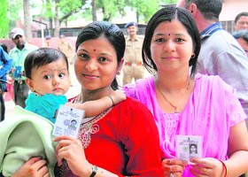 Two women wait for their turn to cast their vote outside a polling booth in Defence Colony in Dehradun