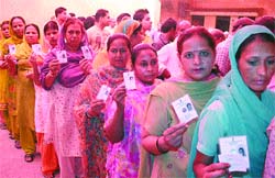 Women show their voters identity cards while standing in a queue outside a polling station to cast their votes in Jalandhar on Wednesday.