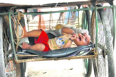 A child kept on a makeshift bed beneath a rehri in Dehradun