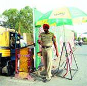 A policeman stands under an umbrella provided by a private player in Amritsar.