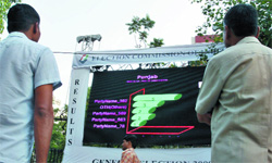 Pedestrians stand near a giant-sized display screen erected in front of the Election Commission of Indias head office to display election results in New Delhi on Friday.