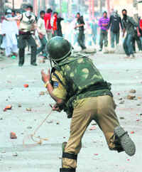 A security personnel responds to heavy stone-pelting by protesters in Srinagar on Friday.
