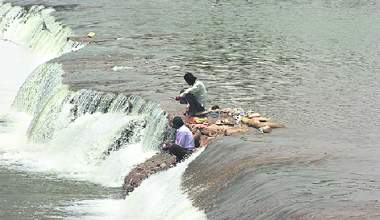 Hoping for a big catch, fishermen perch on a fall in the Tawi in Jammu.