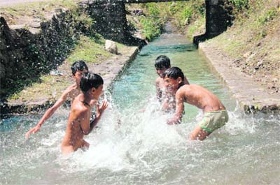 To beat the heat, children enjoy a dip in the cool waters of a canal in Dehradun.