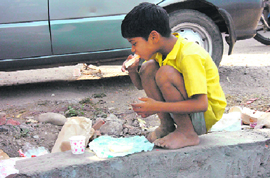 A child eats leftovers at a road pavement in Dehradun on Sunday.