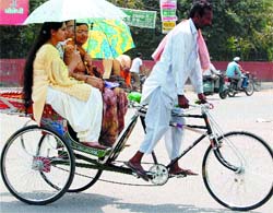 As the temperature soars, girls on a rickshaw take umbrella cover to save themselves from the scorching sun in Amritsar.