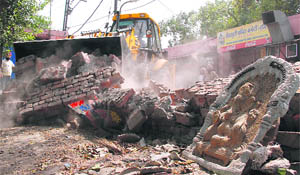 A boundary wall being demolished at Shivpuri in Ludhiana on Tuesday.