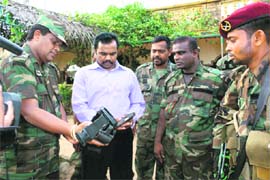 In this photo, provided by the Sri Lankan army, former rebel commander and present government minister Vinay agamoorthi Muralitharan, also known Karuna (centre in plain clothes), inspects the weapons allegedly used by Tamil Tiger leader Velupillai Prabhakaran in Mullaitivu, Sri Lanka.